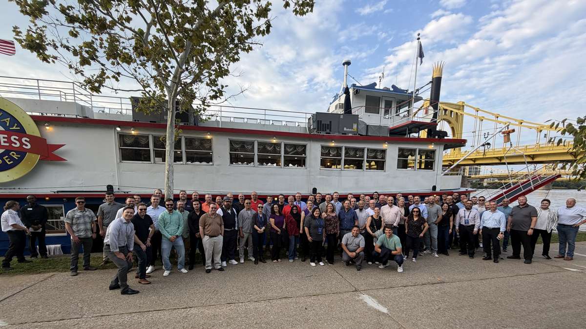 Client Summit 2026 attendees in a group photo at the Gateway Clipper dock in Pittsburgh, with the Roberto Clemente Bridge behind them